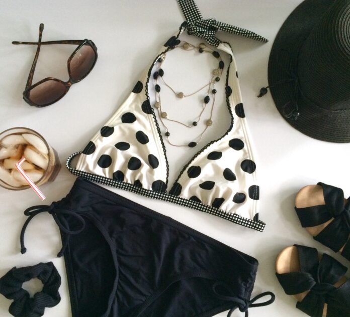 Summer essentials lay flat. Polka dots bikini, & black accessories for beach vacation days