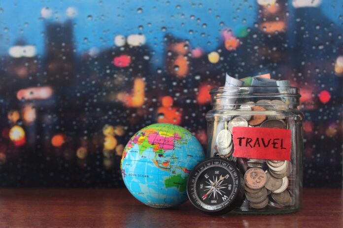 Coins in a glass jar, earth globe and compass with copy space for text.