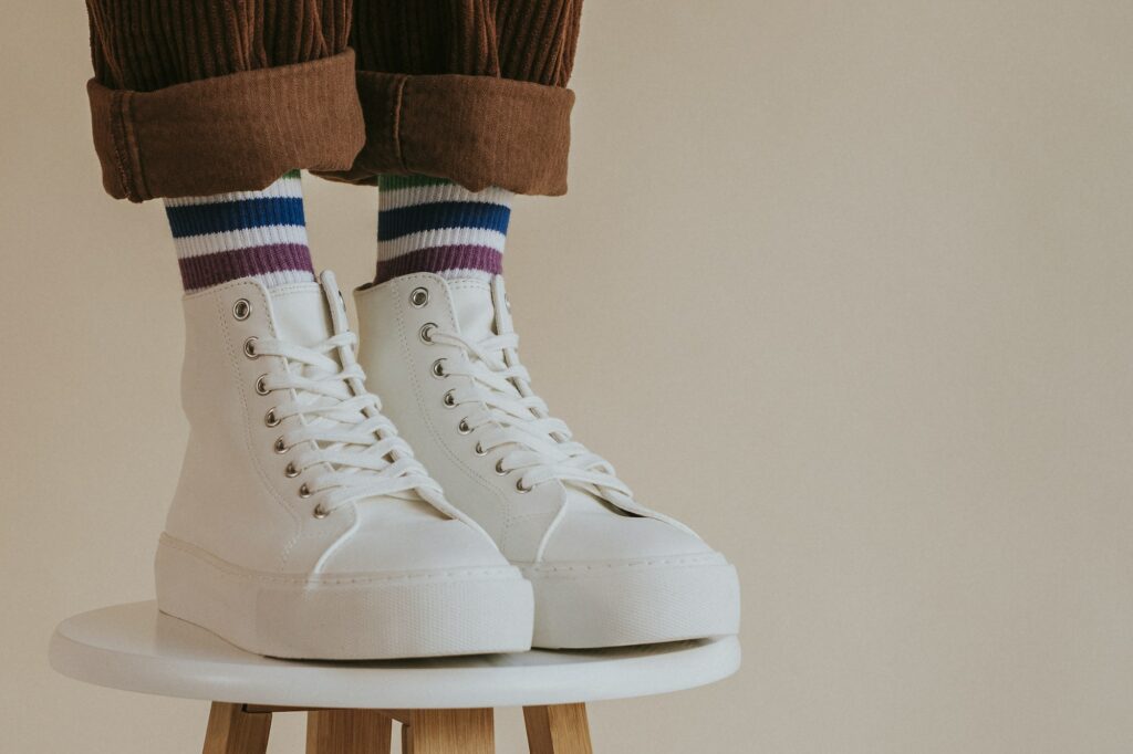 Model in white sneakers standing on chair