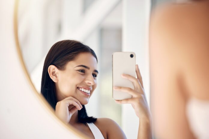 Phone, happy and selfie of woman in bathroom with smile for natural social media picture in mirror.