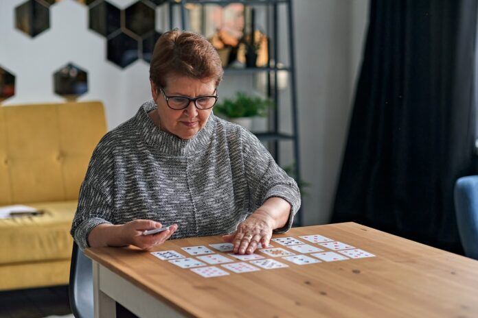 senior woman playing solitaire at home. Happy old lady plays an intellectual game