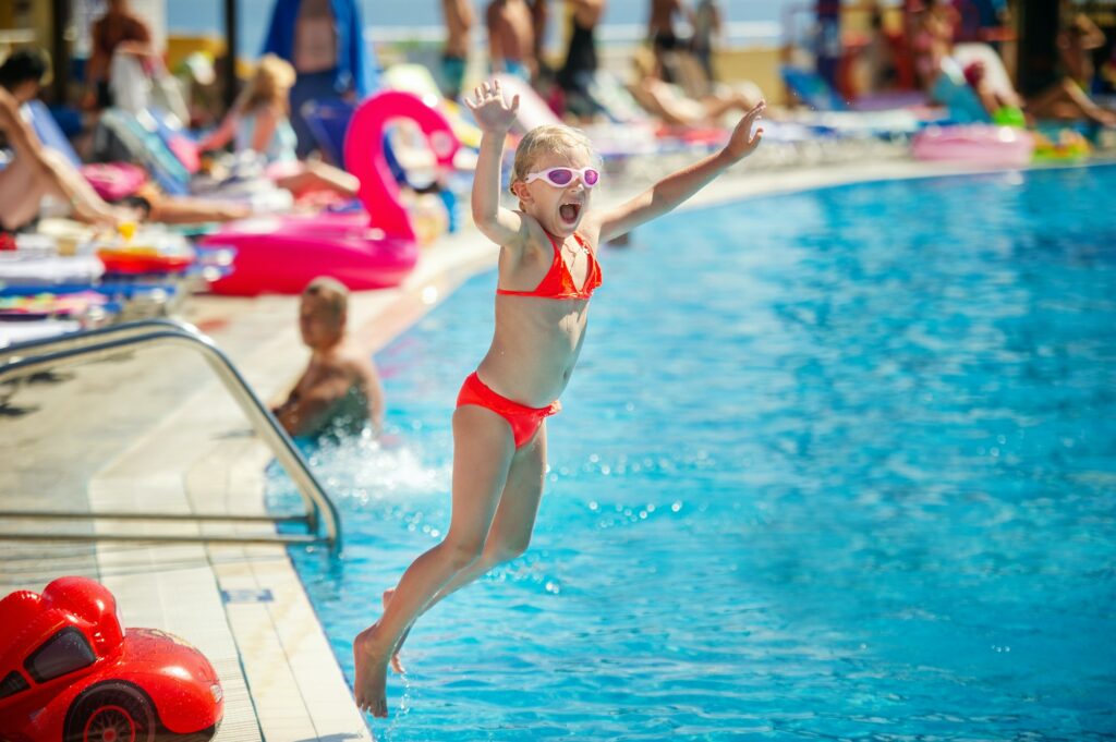 A little girl jumps into the pool at the water park during the summer vacation. Greece