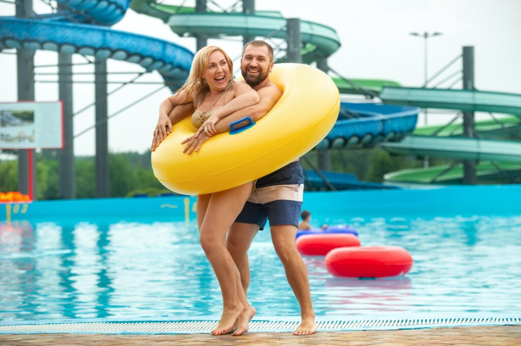 a man and a woman in a rubber inflatable circle stand against the background of a summer water park