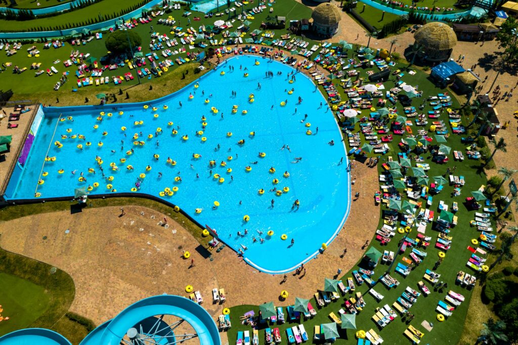 Top view of people relaxing in the pool on yellow inflatable circles and sun beds on the beach