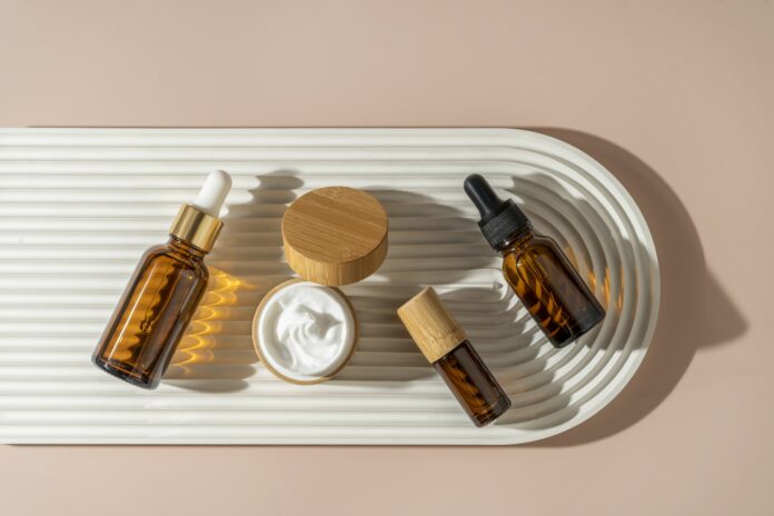 A face or hair serum or essential oil in a brown dropper bottle lying on a white ceramic plate