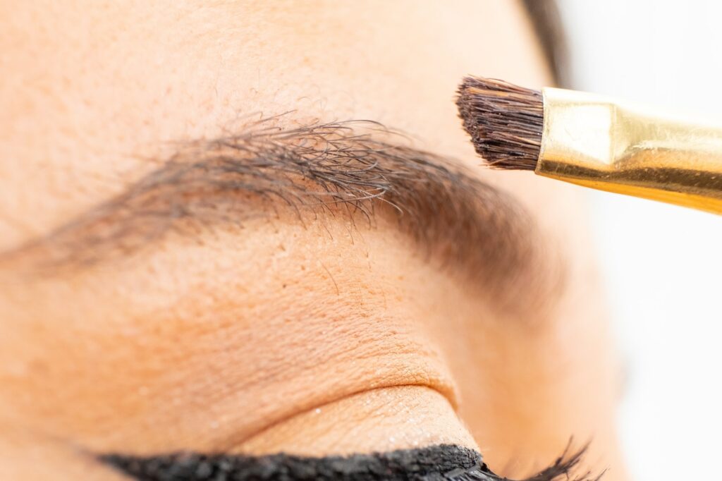 Close up applying brow paste with a brush to eyebrows.