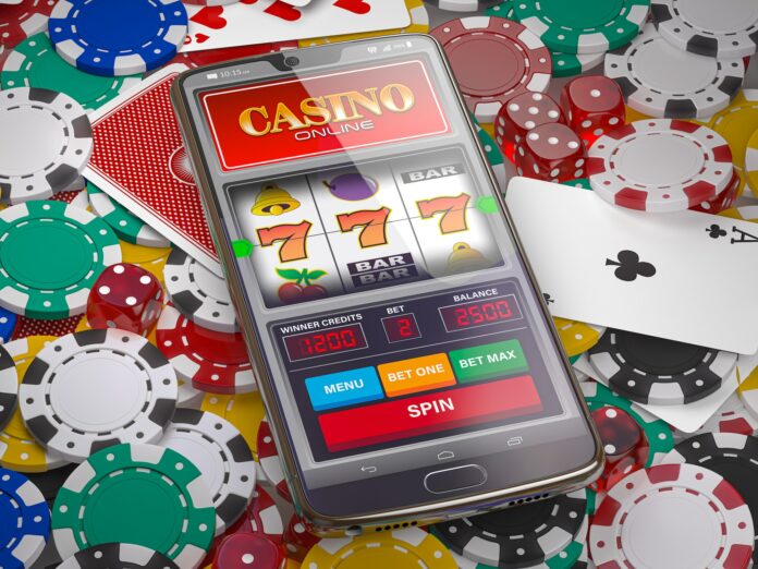 Online casino. Slot machine on smartphone screen, dice, casino chips and cards.