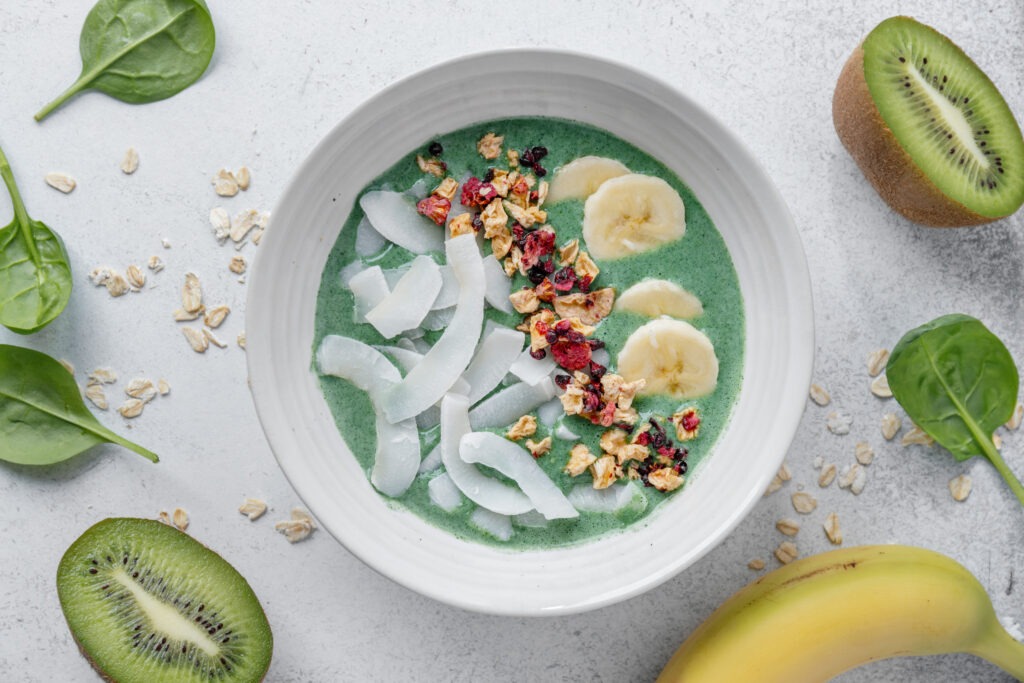 Green smoothie in bowl with fruits