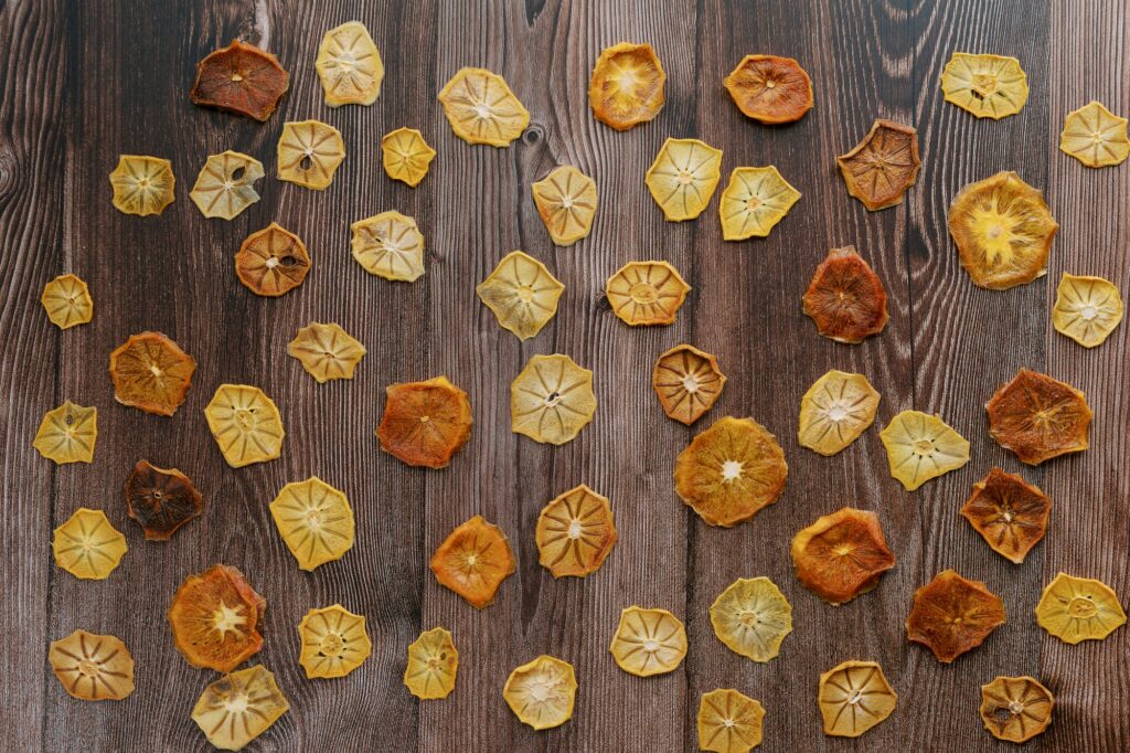 Dried yellow and brown fruit pieces lie on a dark wooden table