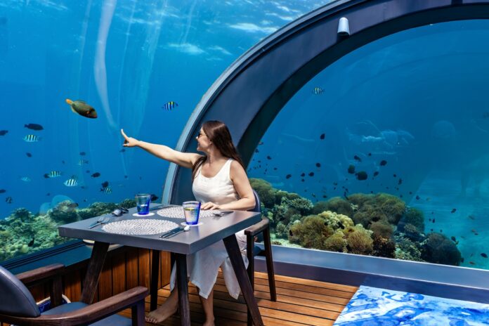 Girl enjoying underwater life in famous 5.8 undersea restaurant on Hurawalhi, Maldives