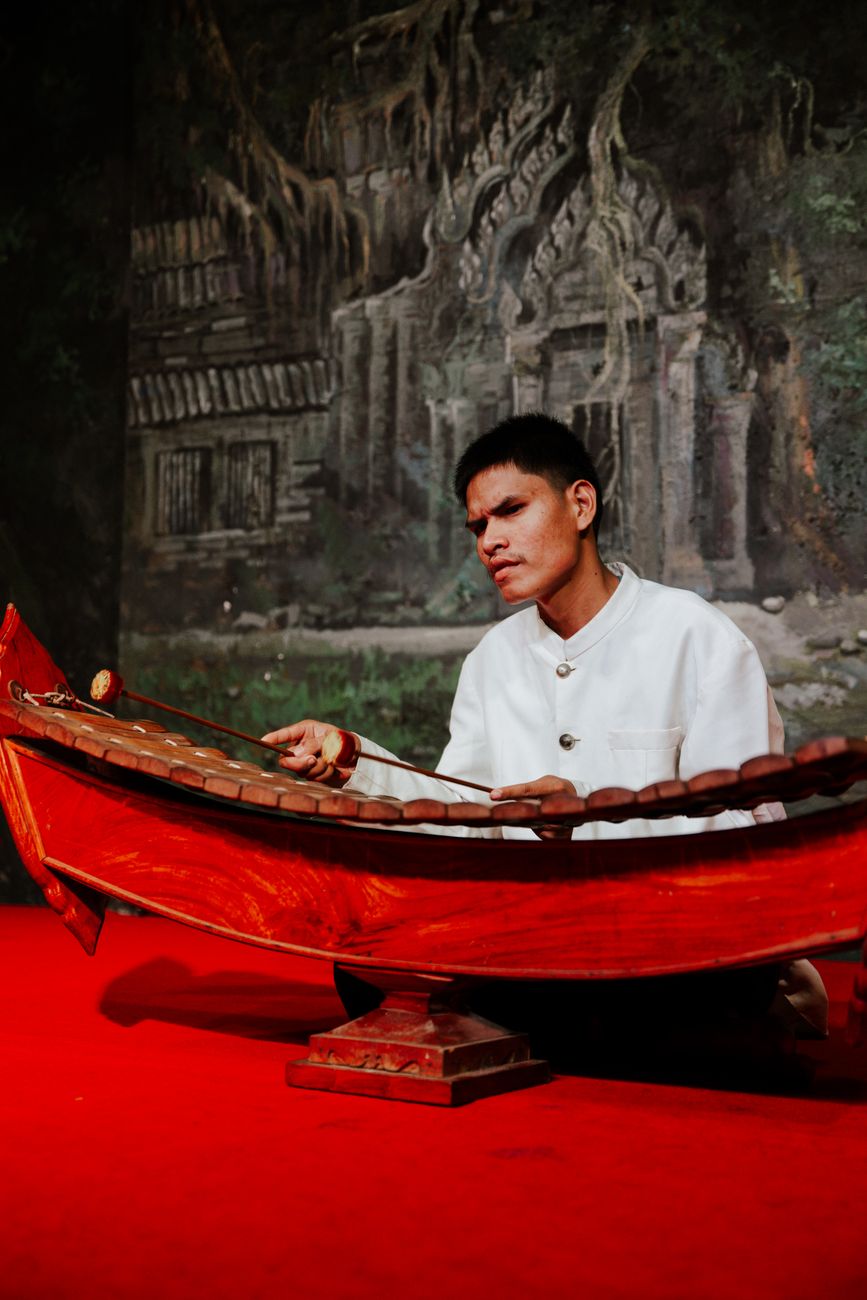 man sitting and playing traditional musical instrument