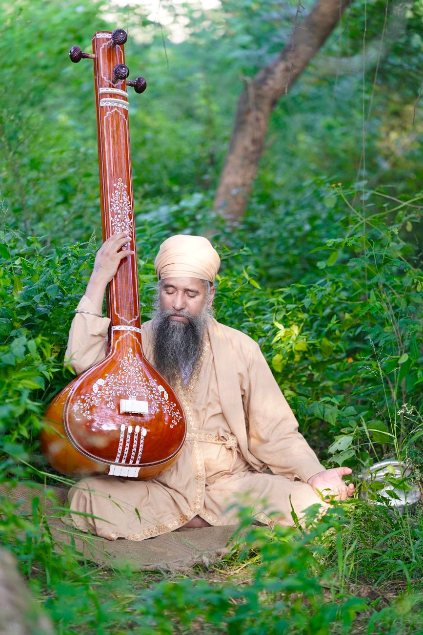 a bearded man in a turban holding a tanpura