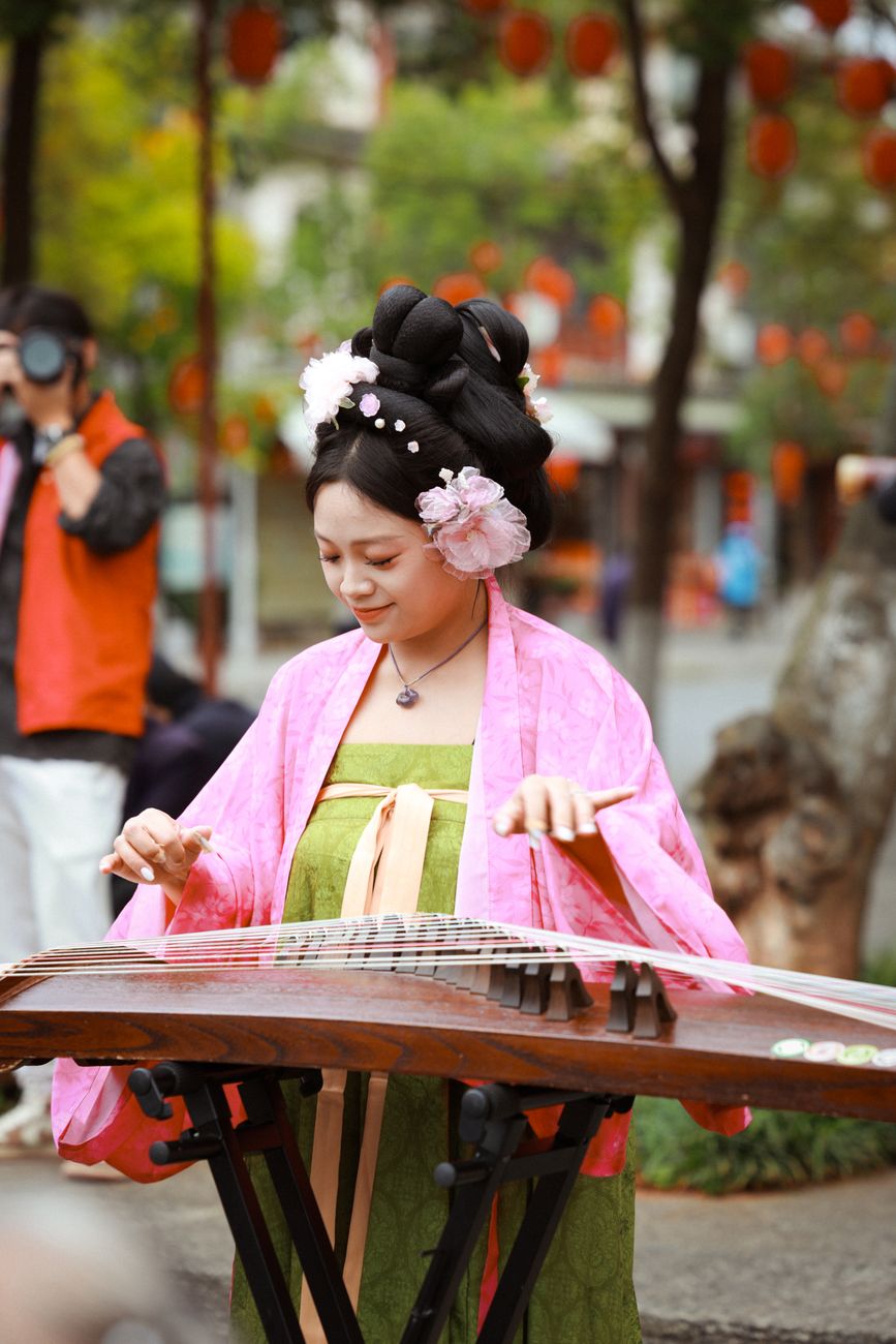 woman playing guzheng in traditional dress