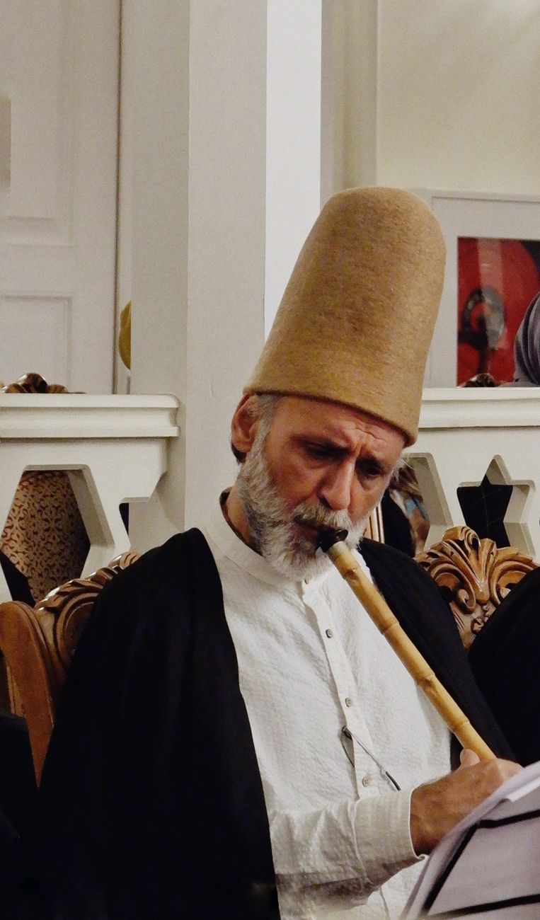 traditional sufi musician playing ney in ceremony