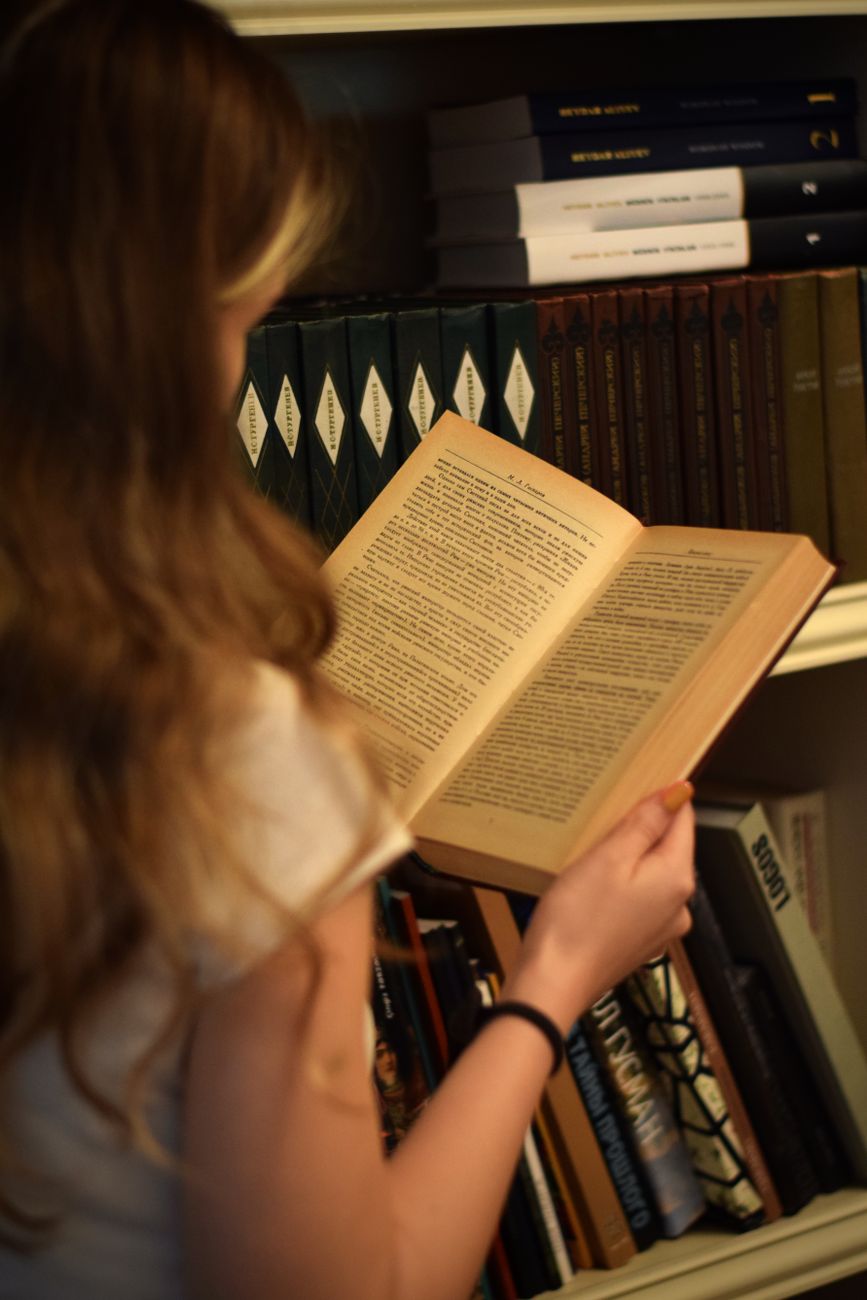 young woman holding a book in a library
